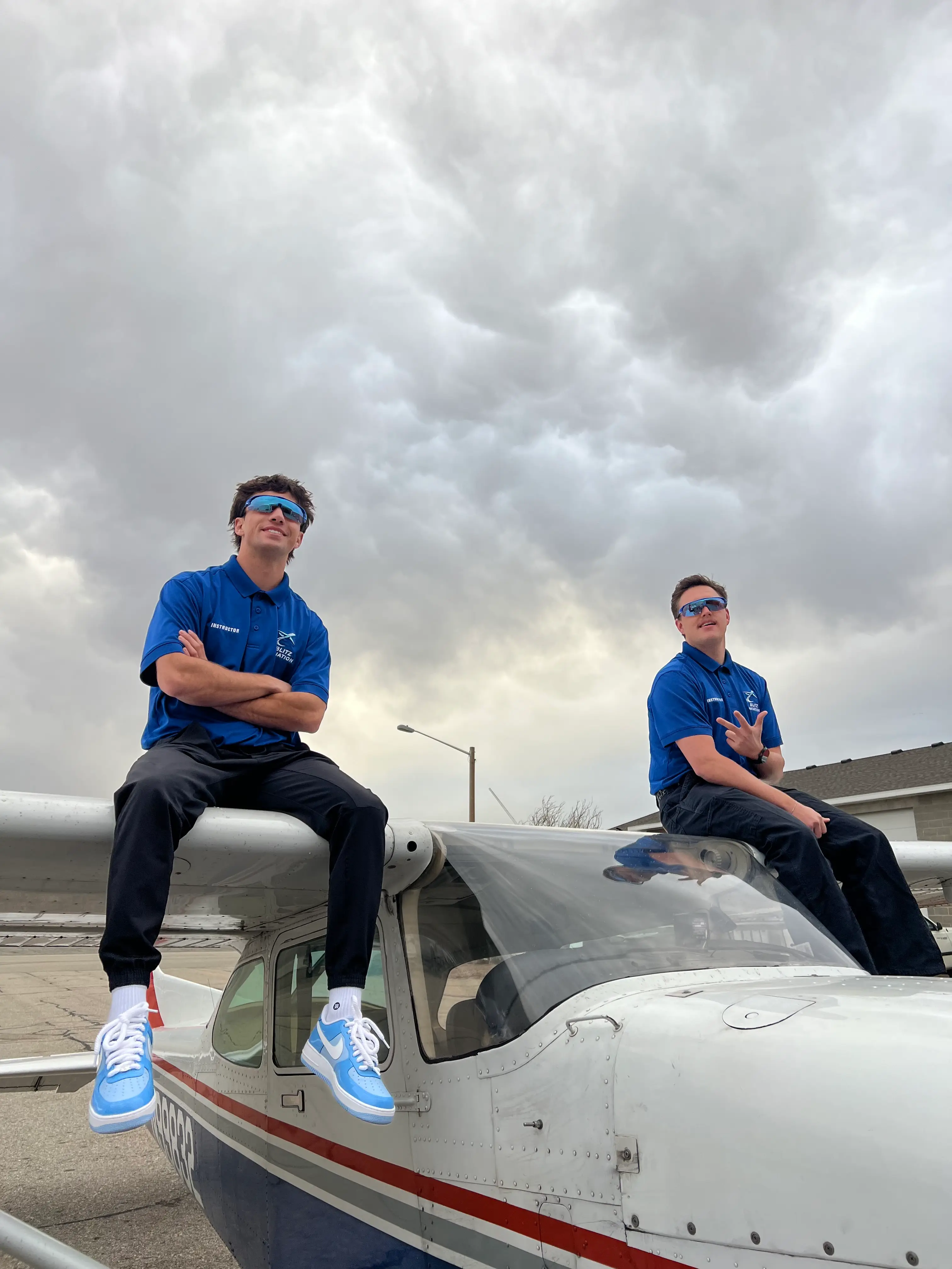 Two Blitz Aviation flight instructors on the wings of a training aircraft, symbolizing the journey to becoming a pilot.