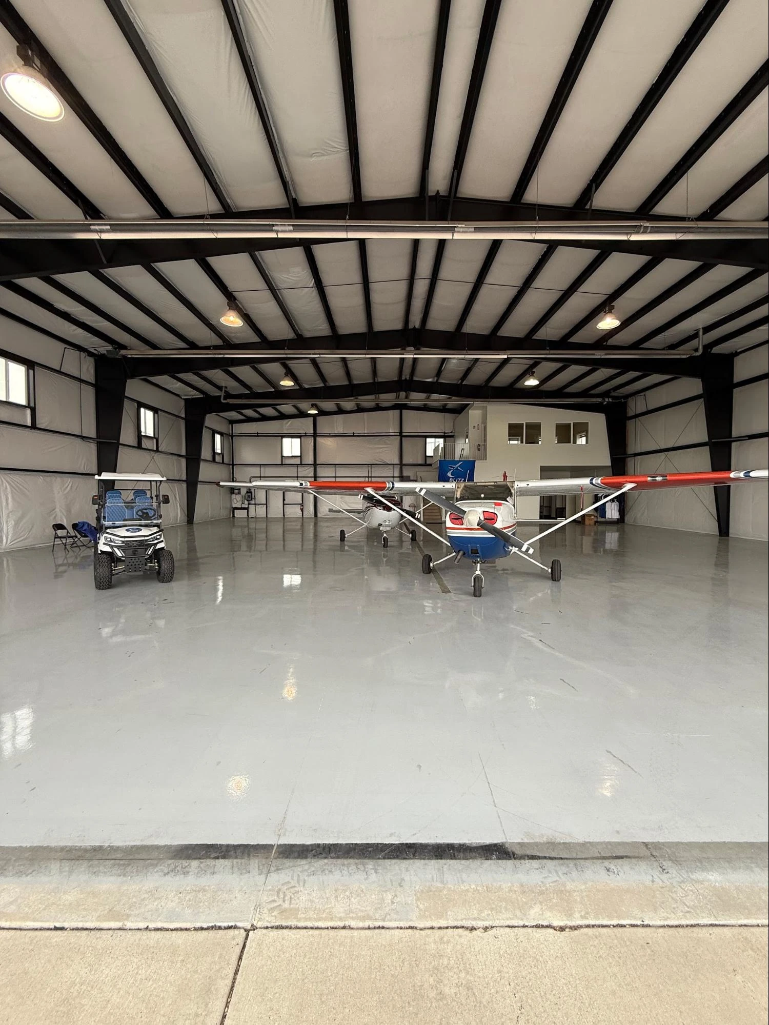 Inside the Blitz Aviation hangar at Ogden-Hinckley Airport with two training aircraft, a utility cart, and a Blitz banner